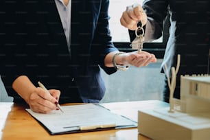 estate agent giving house keys to woman and sign agreement in office