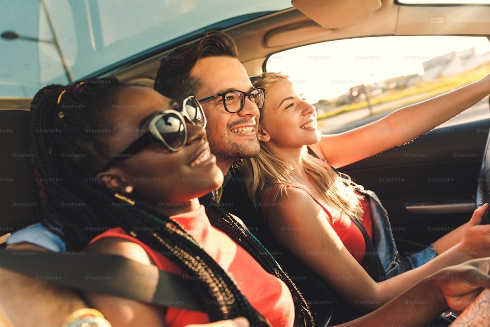 Tres mejores amigos disfrutando de viajar de vacaciones en el coche.