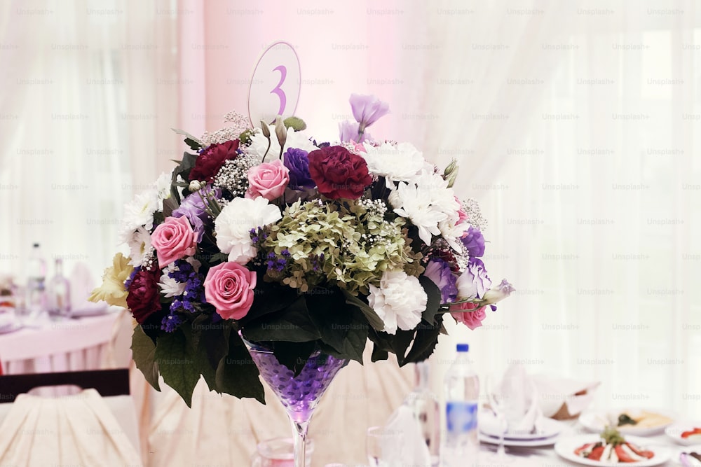 flores em vasos e números de cenário em mesas de casamento com comida no restaurante, recepção de casamento de luxo, decoração elegante e catering. buquês rústicos