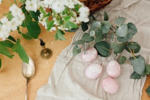 Oeufs de Pâques modernes avec branche d’eucalyptus sur table en bois rustique à plat. Oeufs de Pâques rose pastel élégants peints en teinture naturelle à partir de betteraves. Carte de voeux Joyeuses Pâques