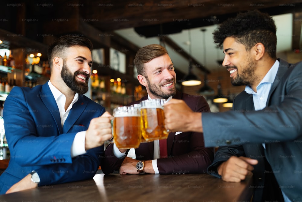 Vecchi amici allegri, uomo d'affari che si diverte e beve birra al bancone del bar in un pub.
