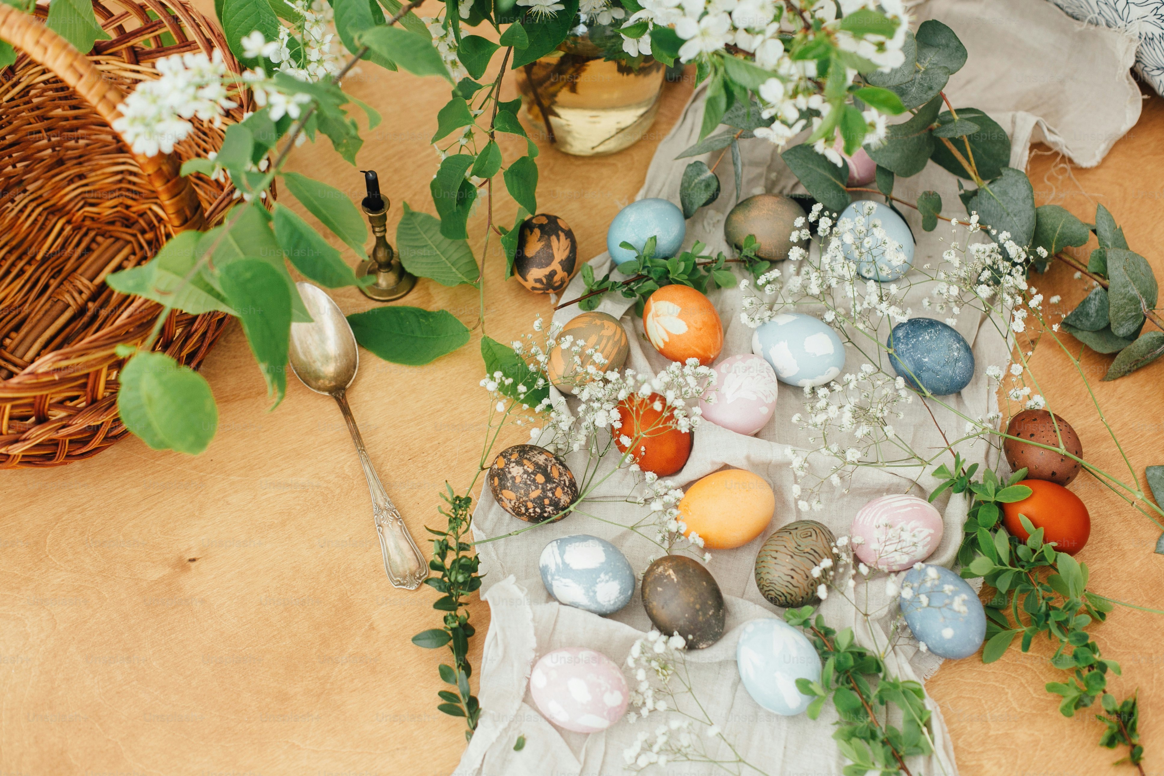 Easter eggs on rustic background with basket, candle, spring flowers and green branches. stylish
