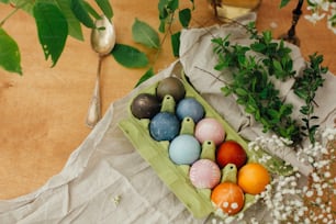 Modern yellow, pink, blue and grey easter eggs painted with organic onion, beets, red cabbage, carcade tea. Zero waste holiday. Natural dye easter eggs in carton tray on rustic table with flowers