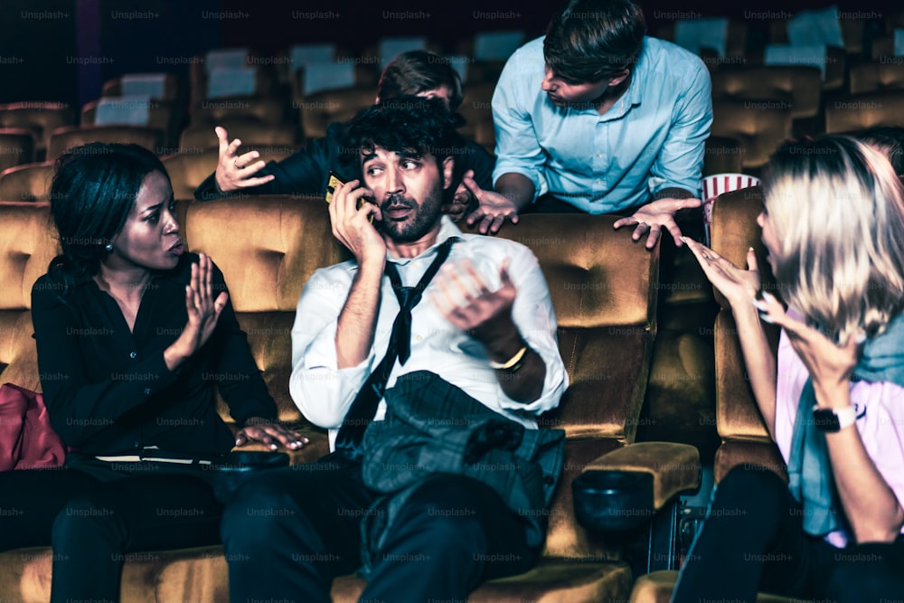 Annoying man talking on the mobile phone at the movie theater people in cinema is angry him