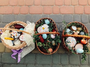 Traditional orthodox Easter food for blessing. Easter baskets with stylish painted eggs, easter cake, ham,beets, butter, candle with boxwood branches for sanctify at church.