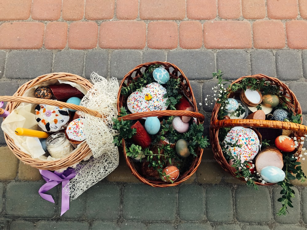 Traditional orthodox Easter food for blessing. Easter baskets with stylish painted eggs, easter cake, ham,beets, butter, candle with boxwood branches for sanctify at church.