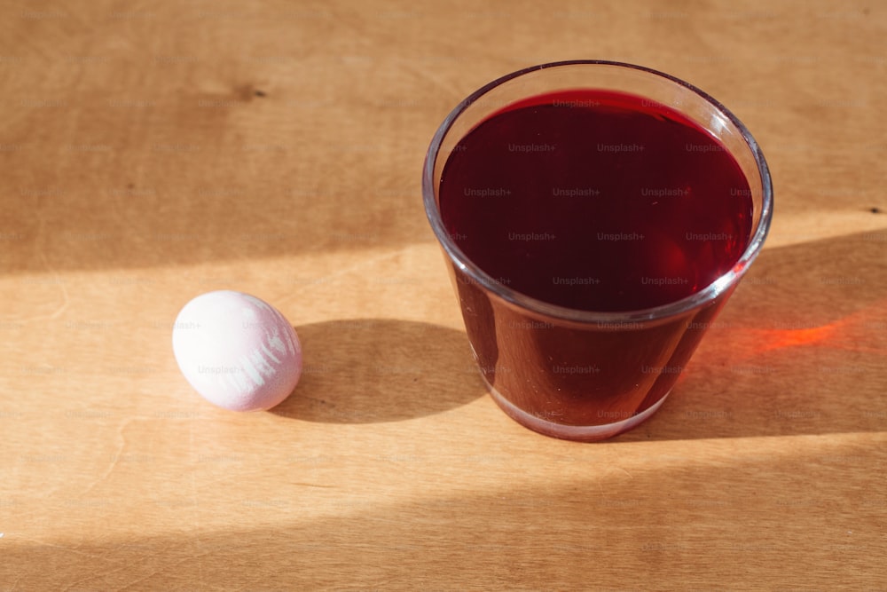 Natural dye easter egg on wooden table in sunny light. Pastel pink easter eggs painted with beetroot, glass jar with red color from beets. Zero waste holiday. Organic ingredients