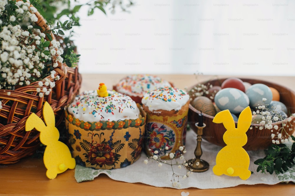 Gâteau de Pâques fait maison, oeufs de Pâques élégants teints au naturel, bougie, décor de lapin, branches vertes et fleurs sur fond en bois. Nourriture de Pâques pour sanctifier. Joyeuses fêtes