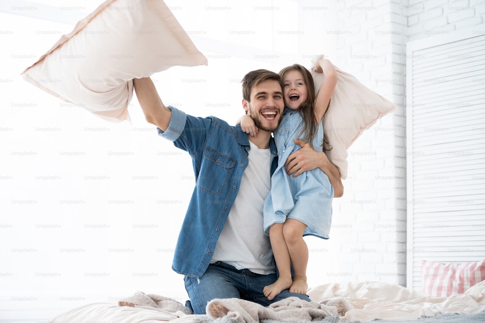 I love you, dad! Happy father and daughter playing pillow fight in bed