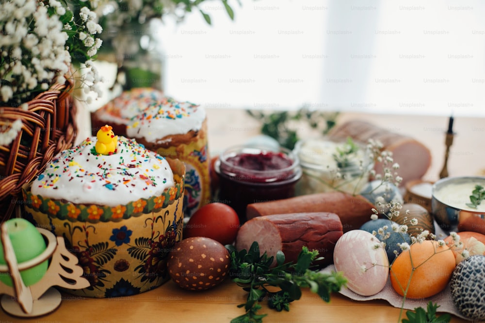 Easter eggs natural dyed, easter bread, ham, beets, butter, green branches and flowers on rustic wooden table with wicker basket and candle. Traditional Easter Food for blessing in church