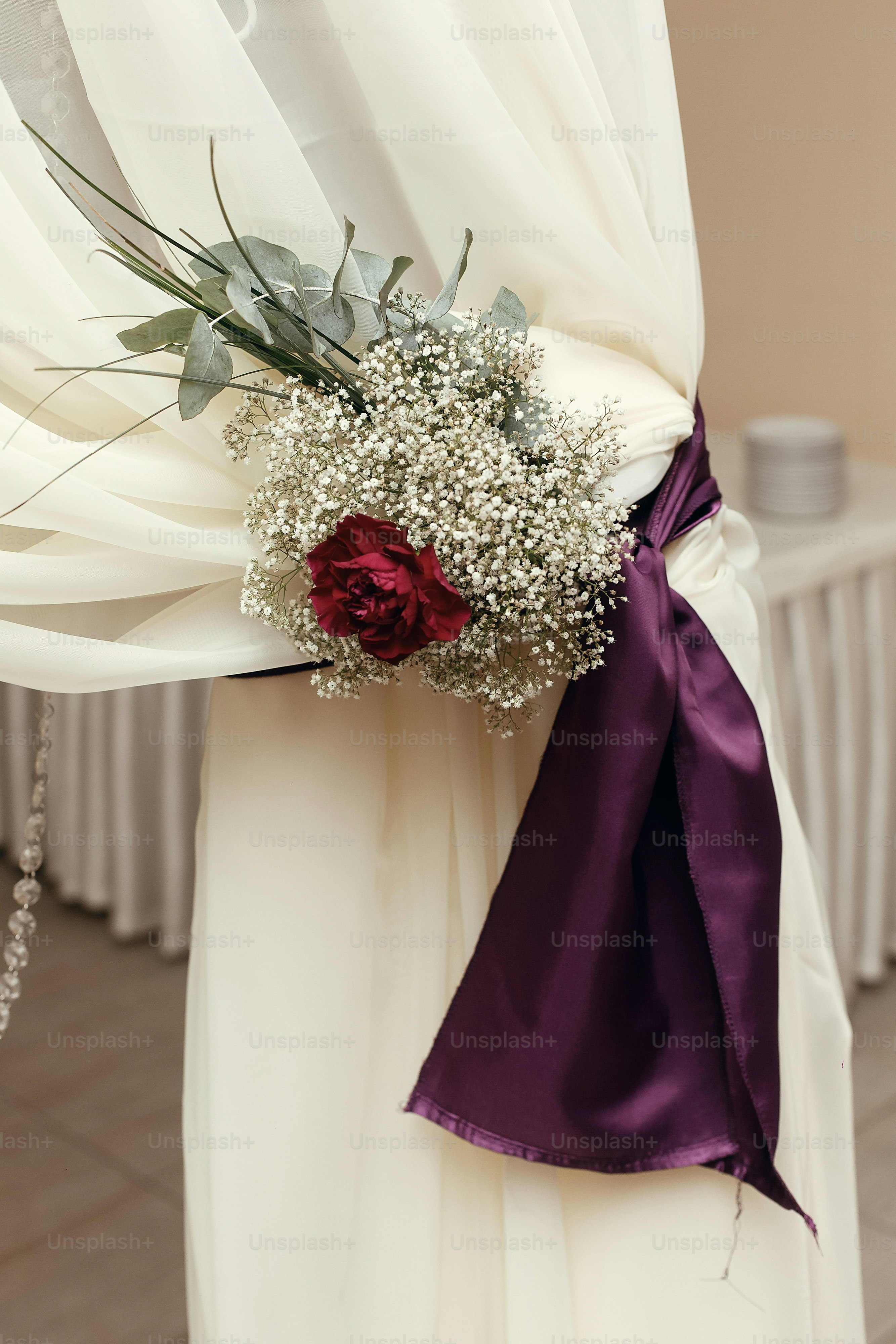 white arch detail with purple ribbons and roses in restaurant, luxury wedding reception, stylish decor