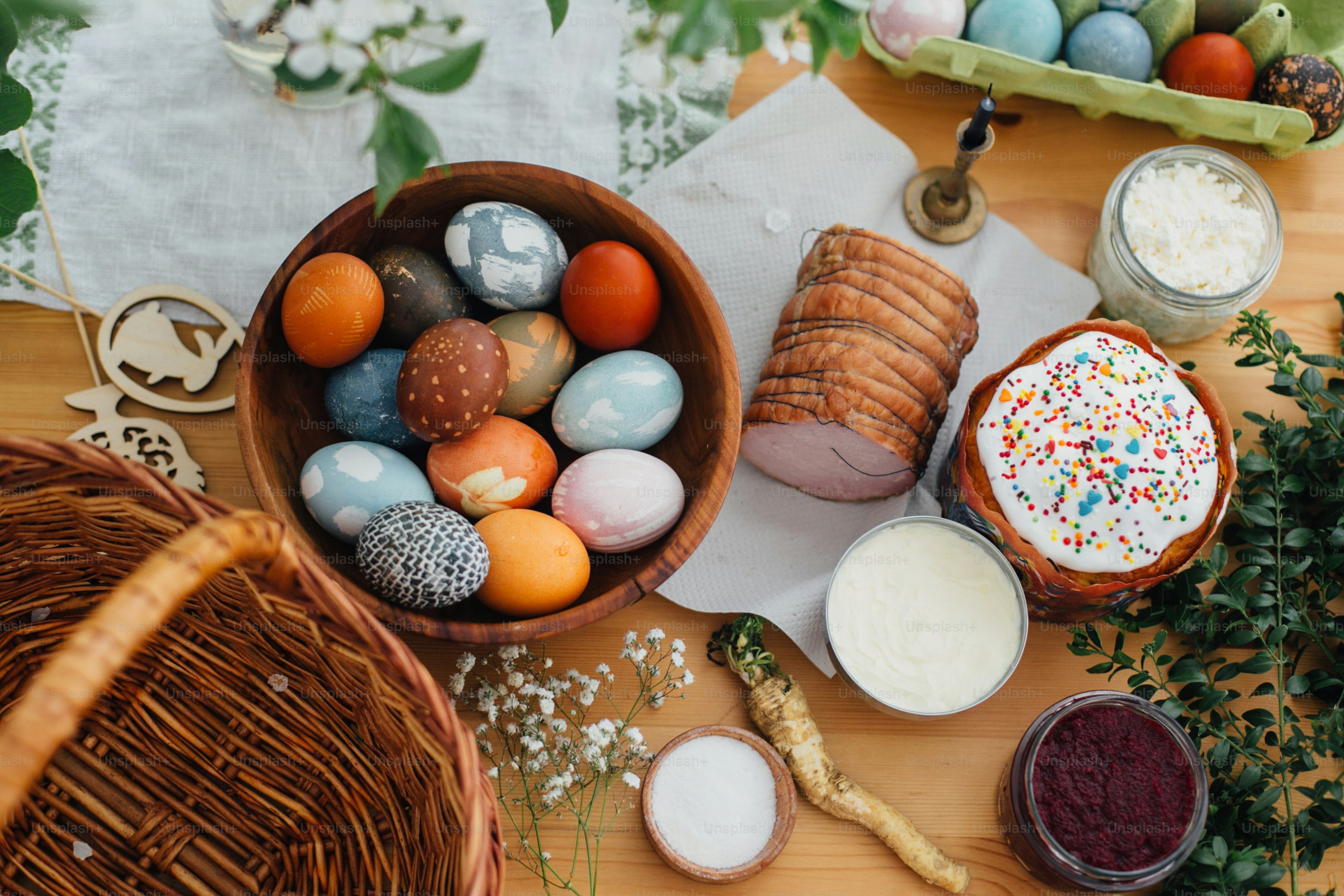 Traditionelles Osteressen flach gelegt. Ostern moderne Eier, Osterbrot, Schinken, Rüben, Butter, grüne Zweige und Blumen auf rustikalem Holztisch mit Weidenkorb und Kerze. Essen zum Segen in der Kirche