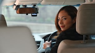 Foto di giovane bella donna d'affari mentre guida un'auto di lusso che va al suo posto di lavoro. Concetto di trasporto personale.