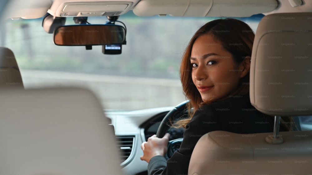 Photo of young beautiful business woman while driving a luxury car going to her workplace. Personal transportation concept.
