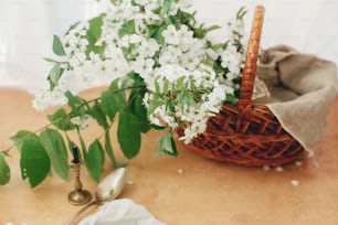 Elegante cesto rustico con telo di lino e rami di ciliegio in fiore in una luce soffusa. Buon concetto di Pasqua. Vacanza eco-friendly. Natura morta rurale