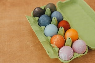 Modern pastel yellow, pink, blue and grey easter eggs painted with organic onion, beets, red cabbage, carcade tea. Zero waste holiday. Natural dye easter eggs in carton tray on wooden table