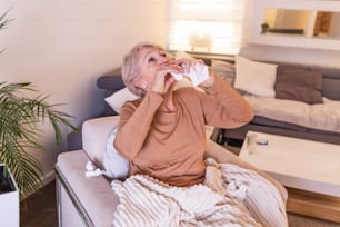 Senior Woman is having allergies and she is using nasal spray to help herself. Elder woman using nasal spray. Nasal spray to help a cold. Sick with a rhinitis woman dripping nose applies nasal spray