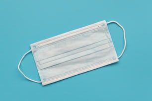 Surgical ear-loop mask on blue background. Top view. Protection concept