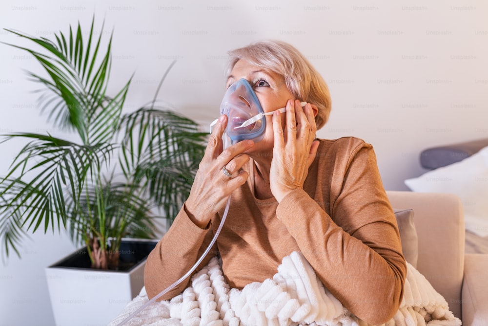病気の高齢女性が吸入をすると、薬は最高の薬です。酸素マスクを着用し、治療を受けている病気の高齢女性。吸入器を持った年配の女性
