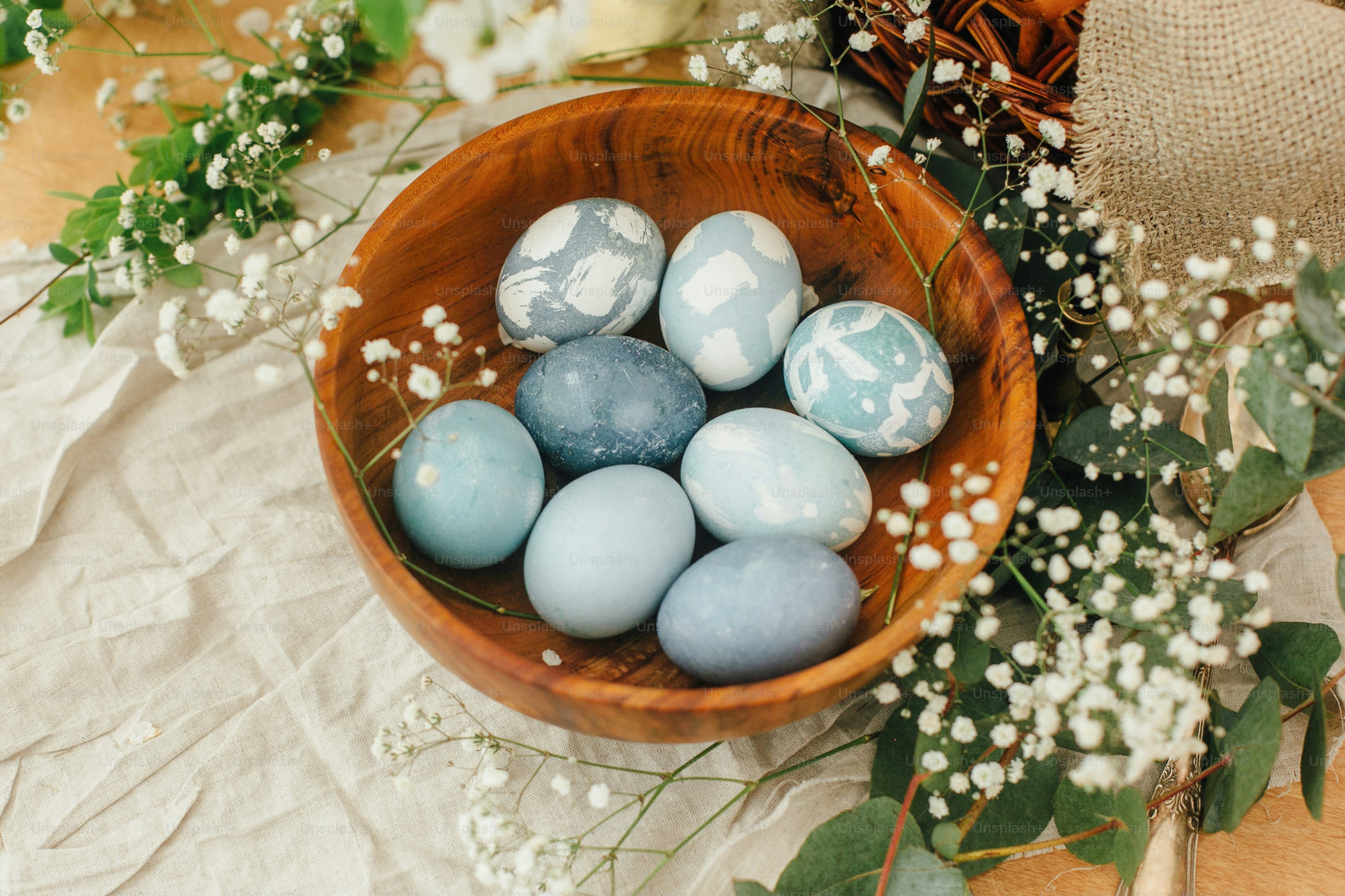 Modern Easter eggs in wooden bowl with spring flowers and eucalyptus on ...