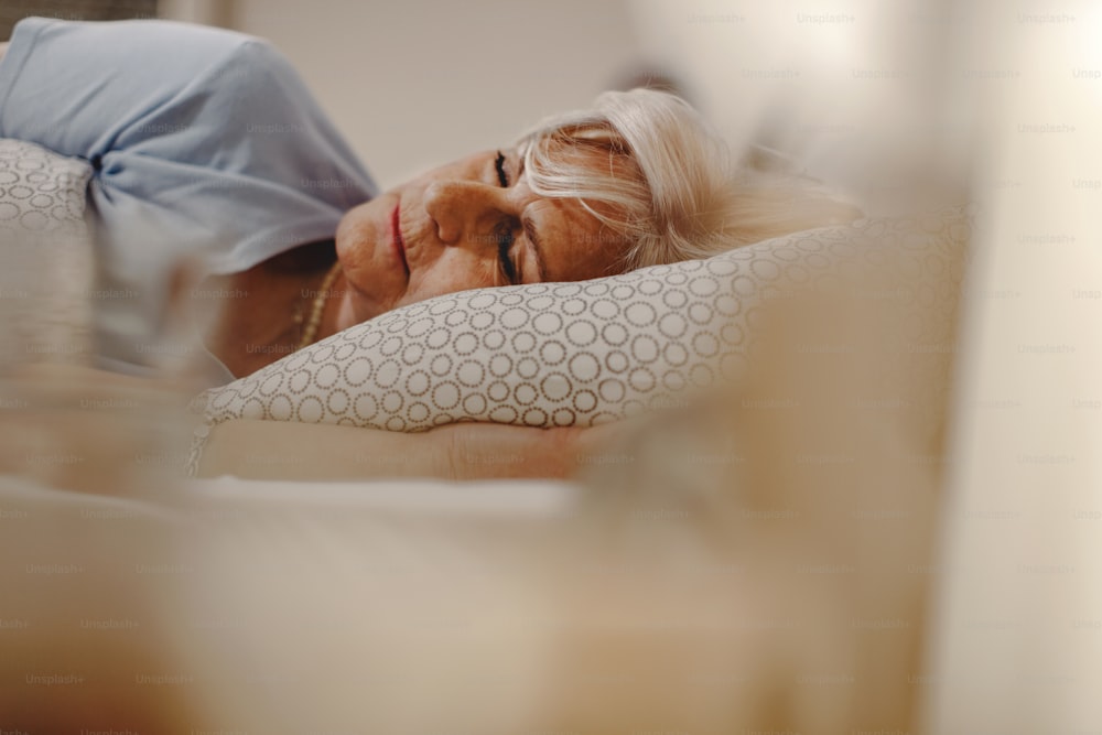 Relaxed mature woman sleeping in the bed at night.