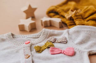 Close up of baby girl knitted clothes on beige background.