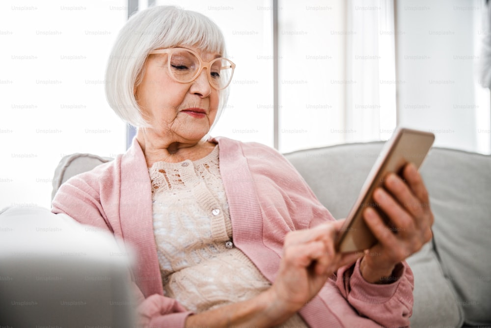 Old woman in glasses texting message on smartphone stock photo