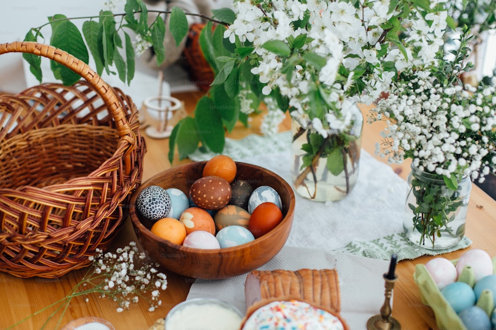イースターエッグは、籐のバスケットとキャンドルと素朴な木製のテーブルの上に、自然染めのイースターブレッドケーキ、ハム、バター、緑の枝や花。教会での祝福のための伝統的なイースターフード