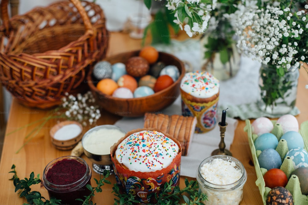 Easter modern eggs, easter bread, ham, beets, butter, green branches  and flowers on rustic wooden table with wicker basket and candle. Traditional Easter Food for blessing in church