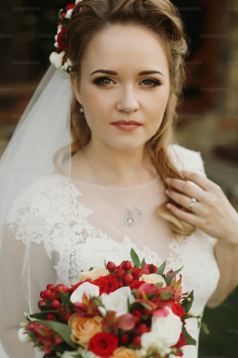 Portrait de belle mariée avec bouquet, magnifique mariée blonde en robe de mariée en dentelle blanche vintage tenant un bouquet de roses rouges, regard sensuel, femme de conte de fées