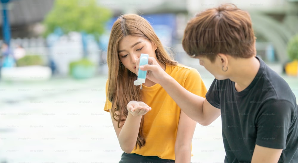 Joven asiático y mujer usando alcohol en gel lavándose las manos y los dedos