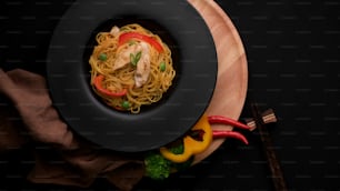 Draufsicht auf Schezwan Nudeln oder Chow Mein mit Gemüse, Hühnchen und Chilisauce serviert im schwarzen Teller
