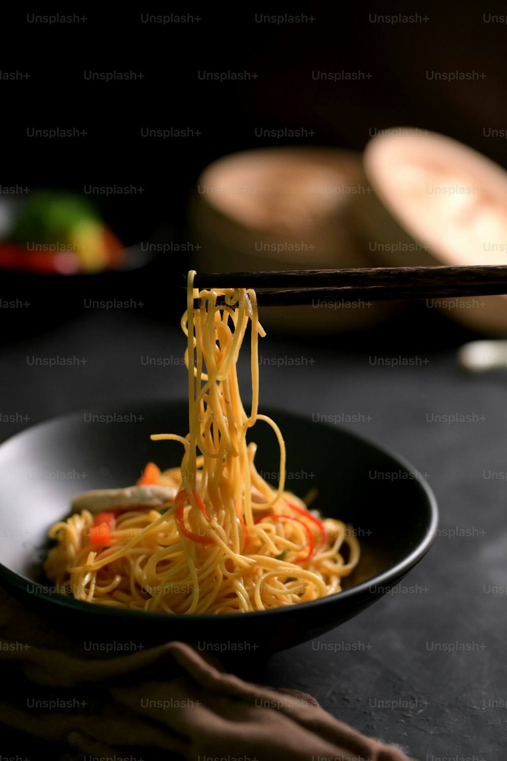 Cropped shot of Schezwan Noodles or Chow Mein, Chinese noodle in black bowl on black table