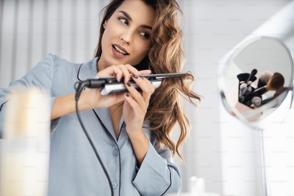 Lächelnde junge Dame Frisur vor dem Spiegel im Zimmer Stockfoto