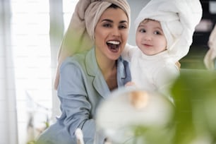 Smiling pretty lady and her kid in towels on their heads and pajamas in the bedroom stock photo