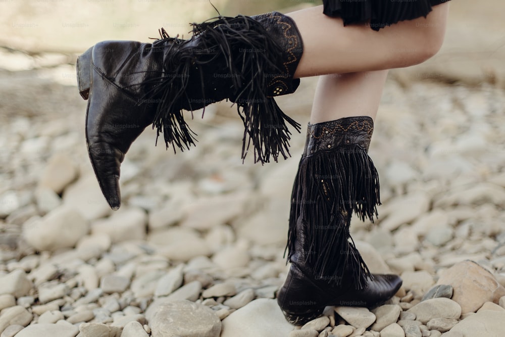 boho girl walking in fringe boot. stylish hipster traveler woman wearing suede boots on river beach. gypsy look. wanderlust summer travel. atmospheric moment. space for text.