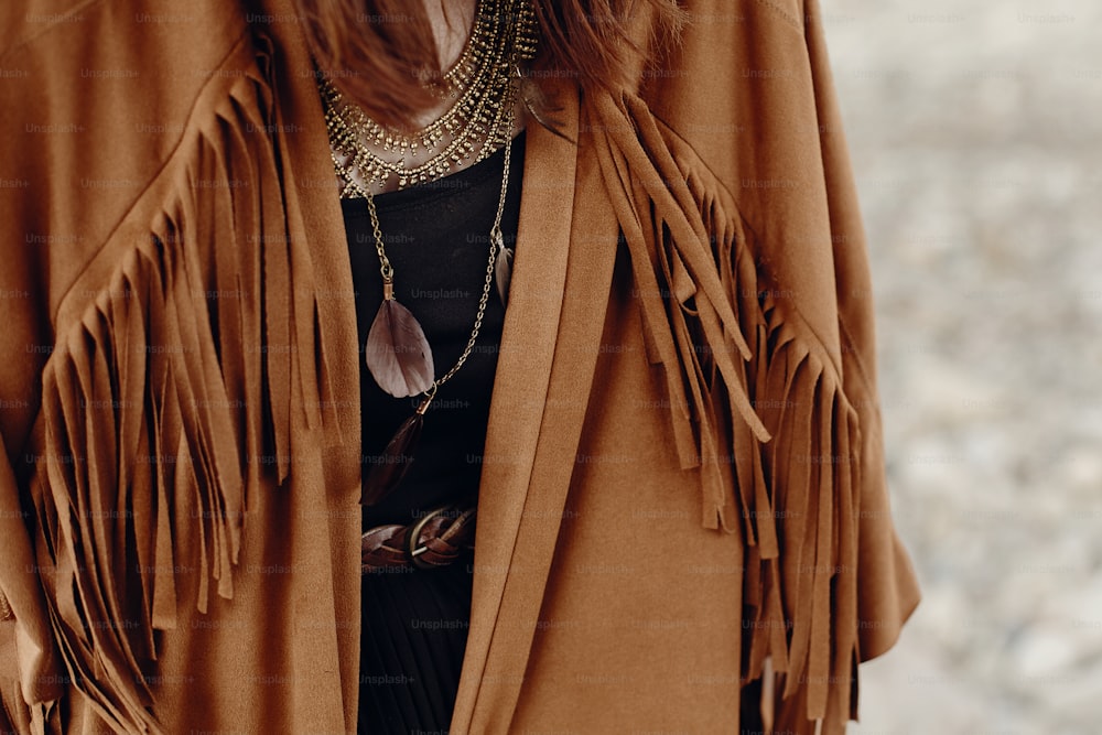 stylish hipster boho traveler woman look. gypsy girl in fringe jacket with feather bronze accessory. wanderlust summer travel. atmospheric moment. space for text.