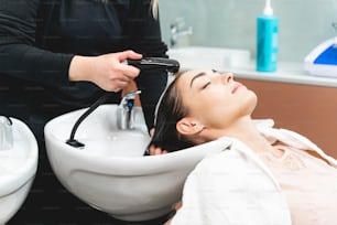 Enjoy the moment. Relaxed young client closing eyes while sitting close to sink while preparing hair for cut