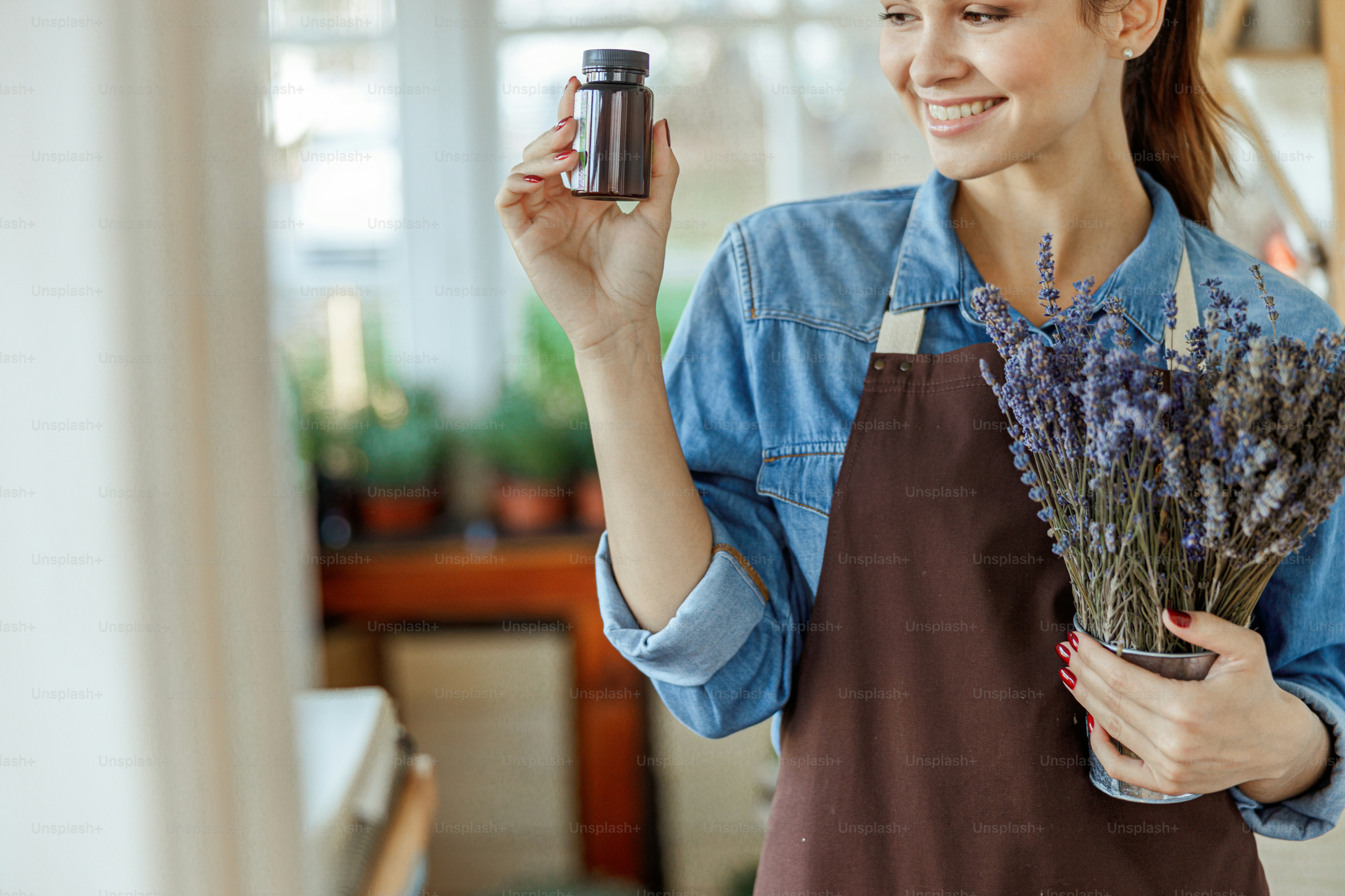 Closeup portrait of a smiling girl with a small bottle of lavender essential oil looking away