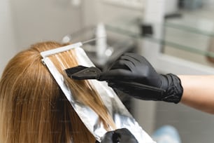 Blonding procedure. Professional female person wearing sterile gloves while coloring hair for her client. Beauty concept
