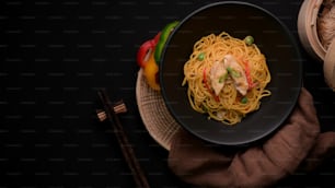 Overhead-Shot von Schezwan Nudeln oder Chow Mein mit Gemüse, Hühnerfleisch und Chilisauce serviert in schwarzer Schüssel