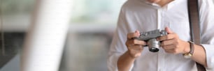 Close up view of young male photographer checking his picture on digital camera while standing in glass wall co-working space