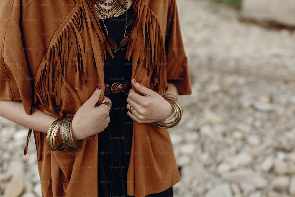 stylish hipster boho traveler woman look. gypsy girl in fringe jacket with feather bronze accessory. wanderlust summer travel. atmospheric moment. space for text.