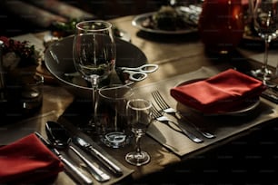 Copos de vinho de luxo e talheres de prata perto de pratos com guardanapos vermelhos close-up - arranjo de mesa de recepção de casamento, marrom, fundo rústico de toalha de mesa, conceito de catering para ocasiões especiais