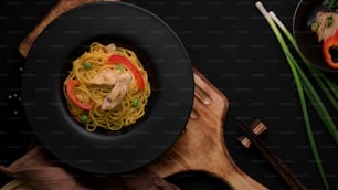 Overhead-Shot von Schezwan Nudeln oder Chow Mein mit Gemüse, Hühnchen und Chilisauce serviert in schwarzem Teller