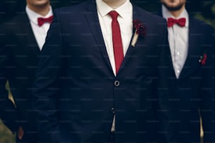 Handsome, successful groom posing with bestmen outdoors, group shot of newlywed groom standing in park with groomsmen in stylish suits