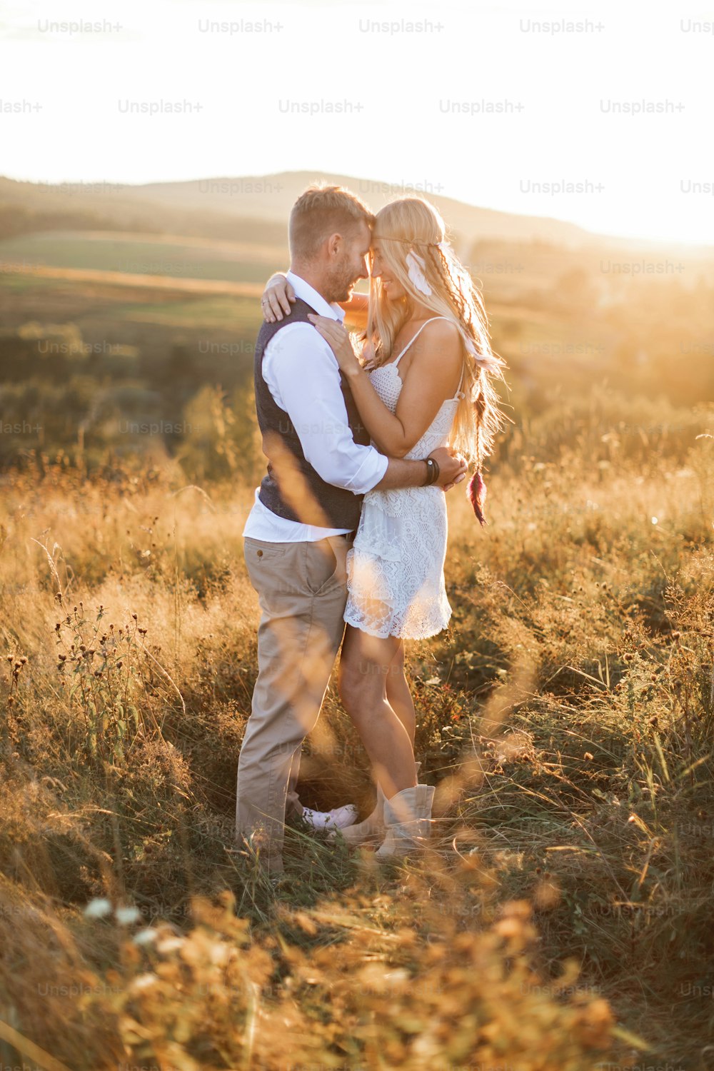 Young hippie boho couple in love outdoors. Portrait of young stylish fashion couple posing in summer in field, hugging and looking each other.