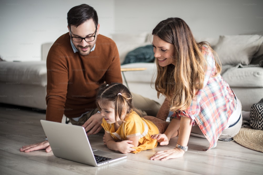 Play, entertainment and learning all in one. Happy family having fun at home using laptop.