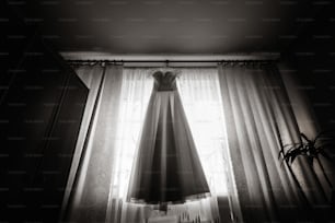 belle robe de mariée blanche de luxe sur cintre sur le fond d’une fenêtre
