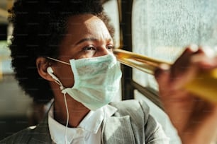 African American businesswoman with face mask contemplating while traveling by public transportation during virus epidemic.
